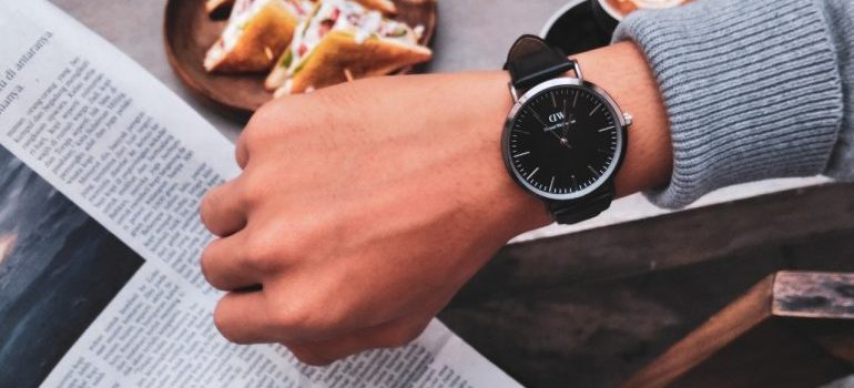 A watch, on the hand of a person reading a newspaper