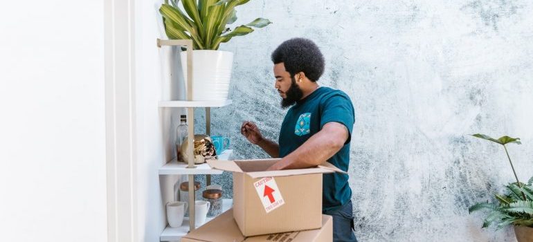 A man in a blue shirt placing items in the box.