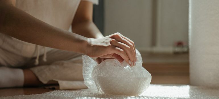 A person wrapping an item in bubble wrap as the way of how to secure when moving fragile items to Fairfax County