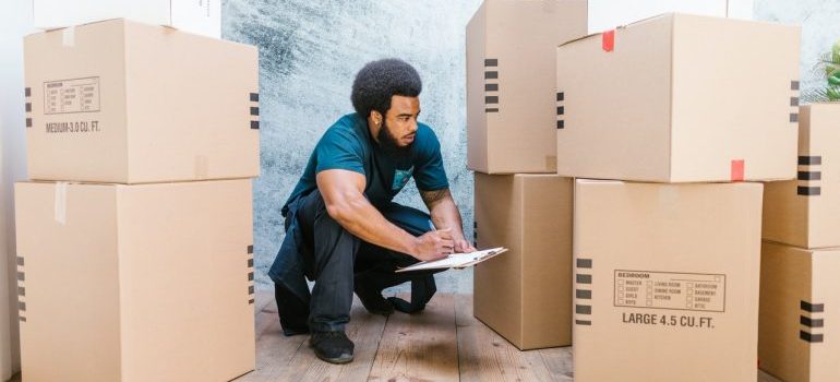 A mover making a list and looking at moving boxes