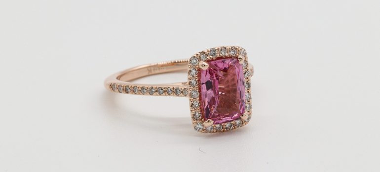 a golden ring with a pink rock in its center 