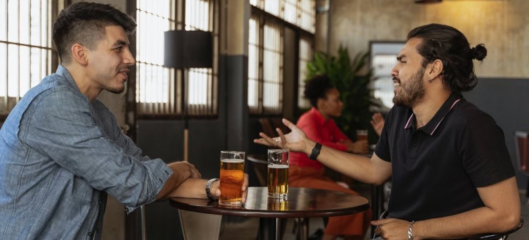 two friends talking to each other in a bar