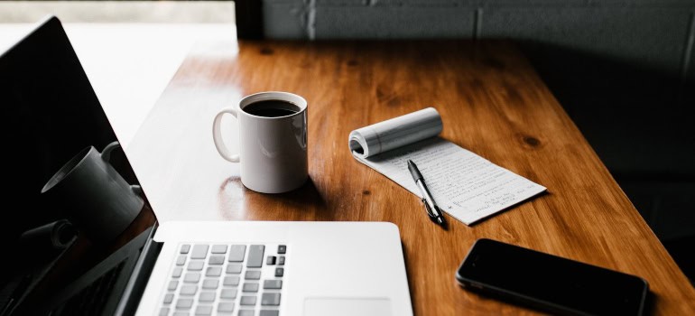 laptop, a phone and a notebook on the table