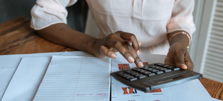 Person in white dress using a calculator to decide Is Lorton a good place to live