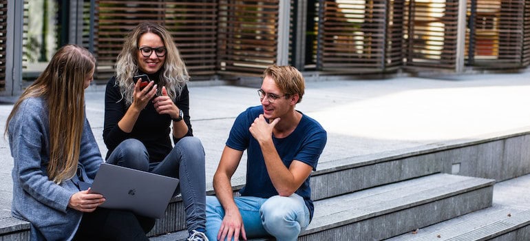 Three people sitting on stairs while talking with each other