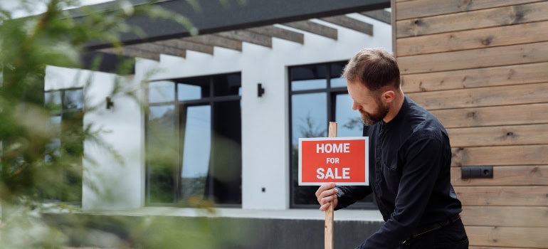 A man placing the "Home for sale" sign