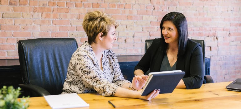 Two women sitting in the office and talking 