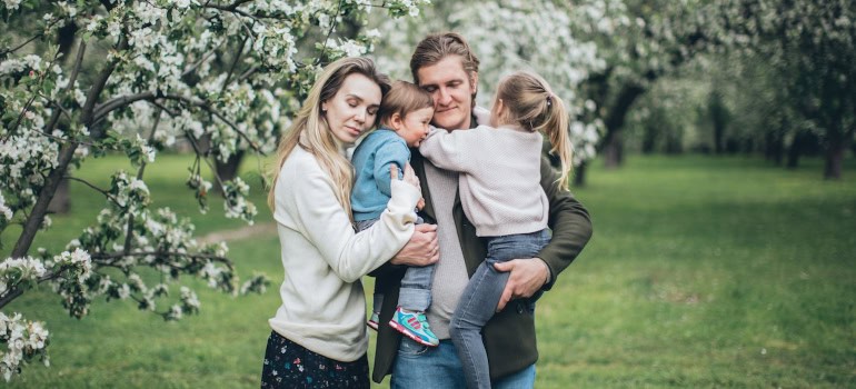 A family of four hugging among the blossoming trees.