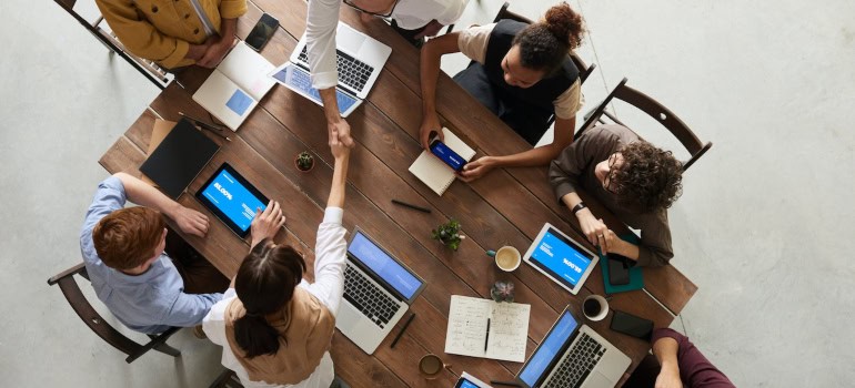 A picture of people exchanging information in a meeting, which is a good strategy when trying to keep employees happy during a corporate relocation.