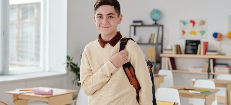 A schoolboy with a backpack in a classroom.