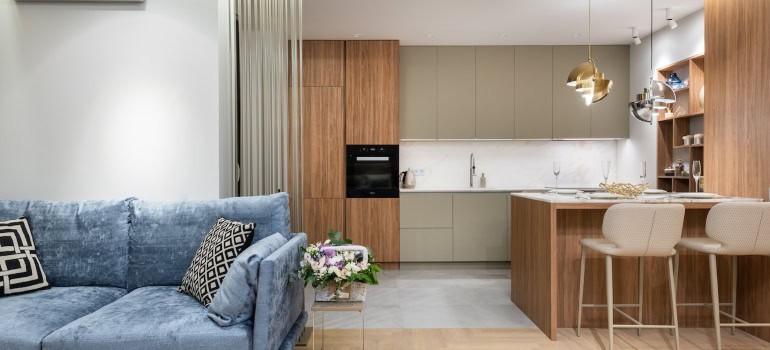 An expertly staged home with a blue sofa and beige kitchen.