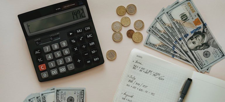 A calculator, piece of paper, pen, and money someone is using to compare the cost of living in Mount Vernon vs. Fort Belvoir