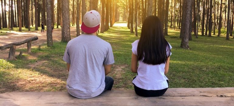 man and woman sitting on the bench in the woods