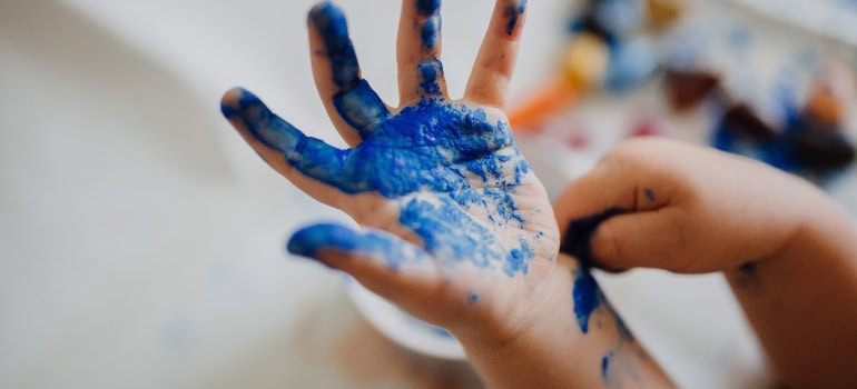 A child's hand covered in blue paint.