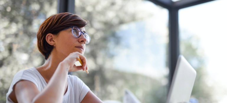 a woman thinking while working on a laptop