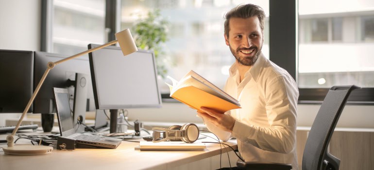 A man sitting at his desk and smiling while holding some papers.