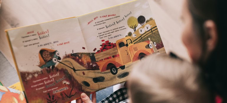 a mother reading from a colorful book to a child