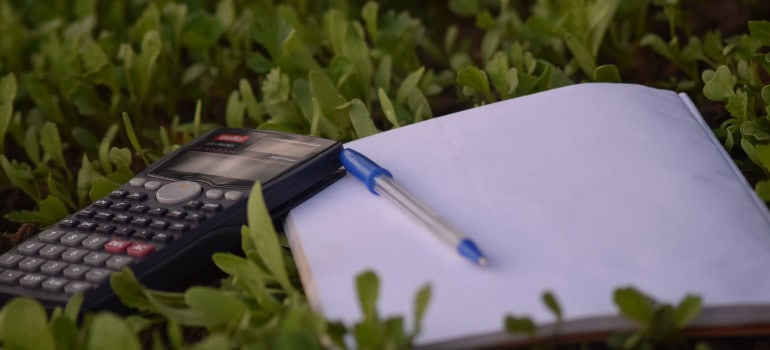 a calculator, notebook, and pen on the grass