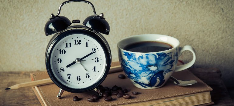 a classic clock and a cup of coffee next to it