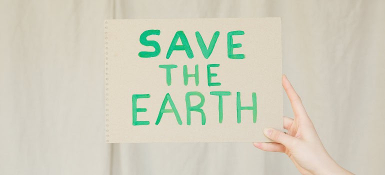 a person holding a piece of paper with the words "save the earth" written on it