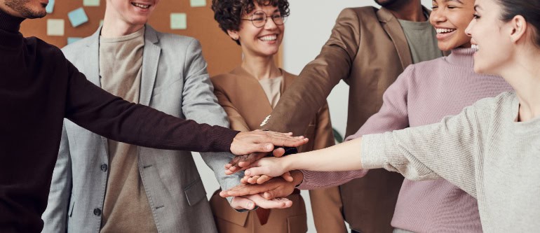 several very different people joining hands 