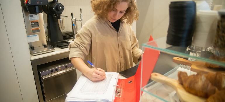 a woman writing something in a large inventory book