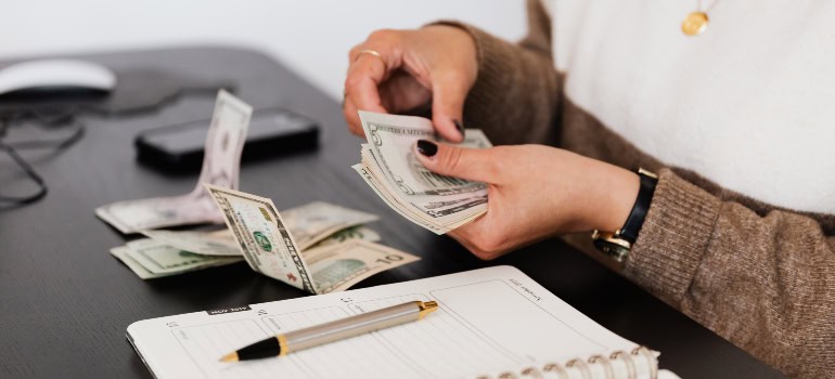 a woman counting dollar bills while sitting at a desk