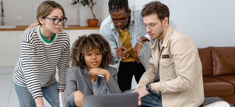 several colleagues talking about something while looking at a laptop