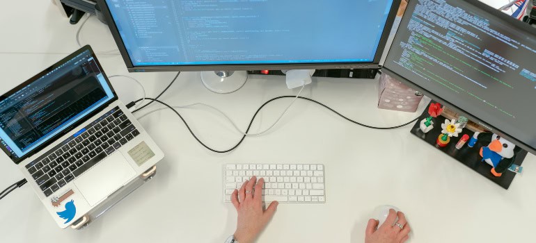 a person coding on three computers after moving from Springfield to Lorton