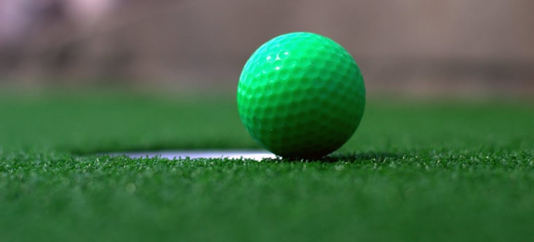 a green golf ball next to a hole