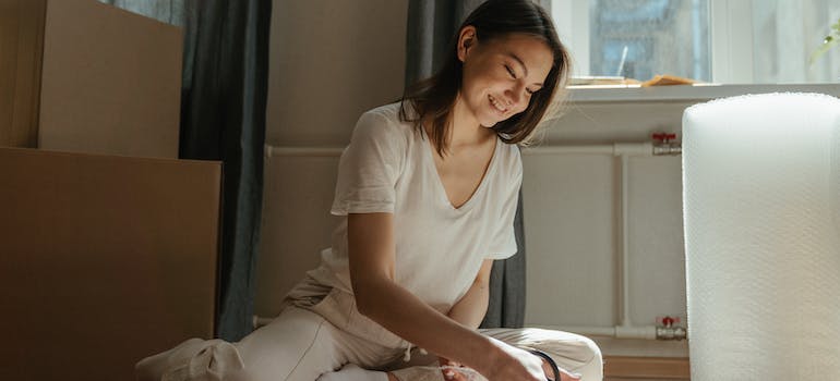 a woman with a smile working with some packing materials that are scattered around her