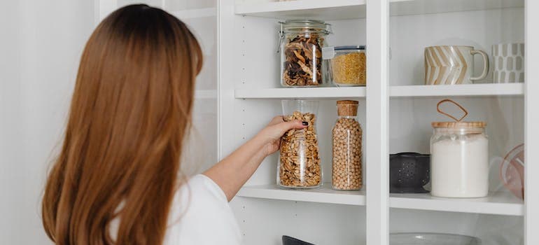 a woman taking a jar full of some food from the pantry