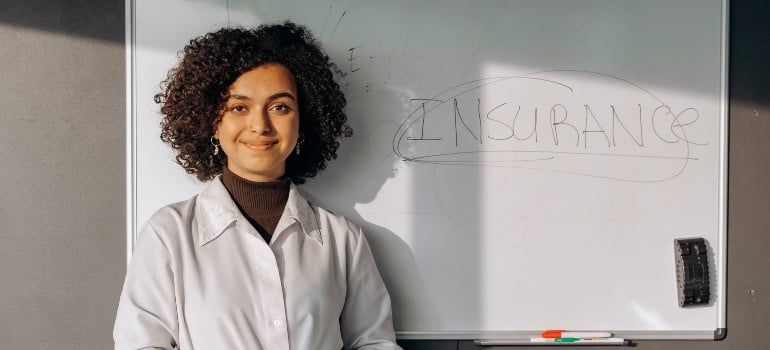 a woman standing in front of the whiteboard with the word "insurance" written on it
