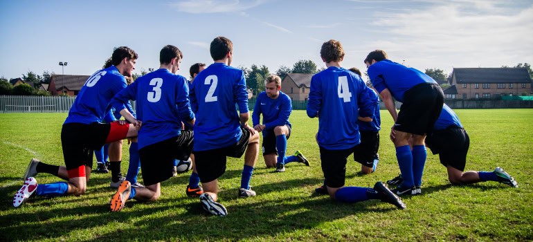 soccer players in blue jerseys gathered together on the pitch