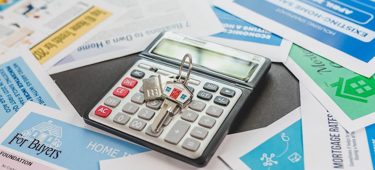 a calculator and a house key on top of it, and many colorful pieces of paper around them