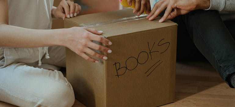 two people handling a box that has the word "books" written on it