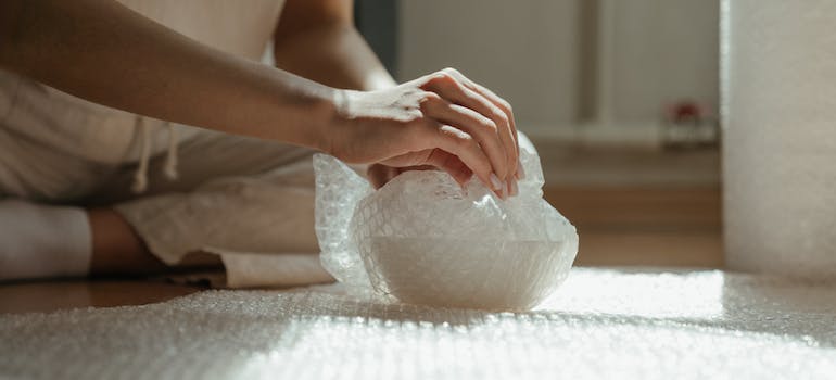 a woman wrapping a delicate item into a bubble pack