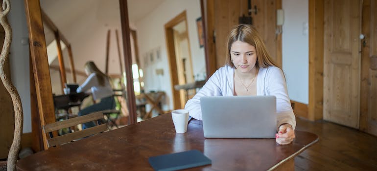 a woman working on her laptop with mirrors on her left making the room bigger