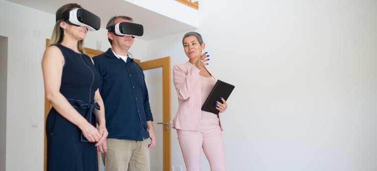 a real estate agent giving two potential buyers a virtual tour, which is something you should consider if you want to sell your old home in Centreville