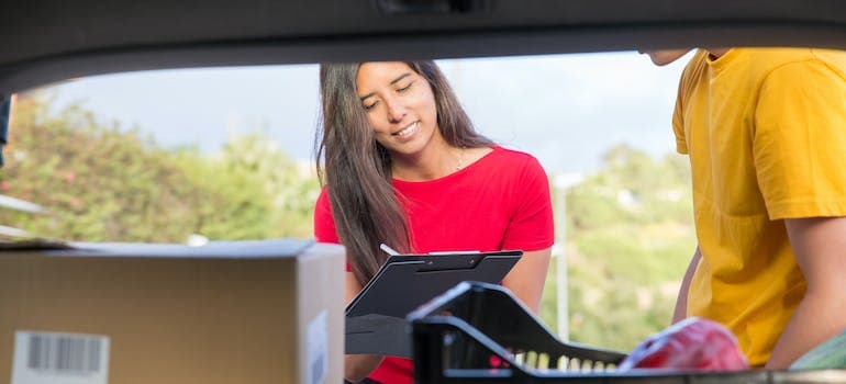 a woman standing in front of a van and making and completing her inventory list