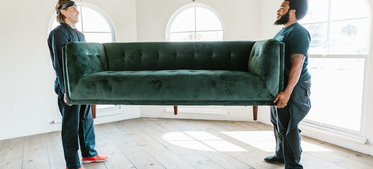 two professional movers, carrying a green sofa