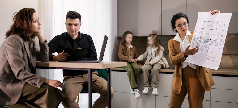 a real estate agent showing blueprints of a house to a couple with 2 kids