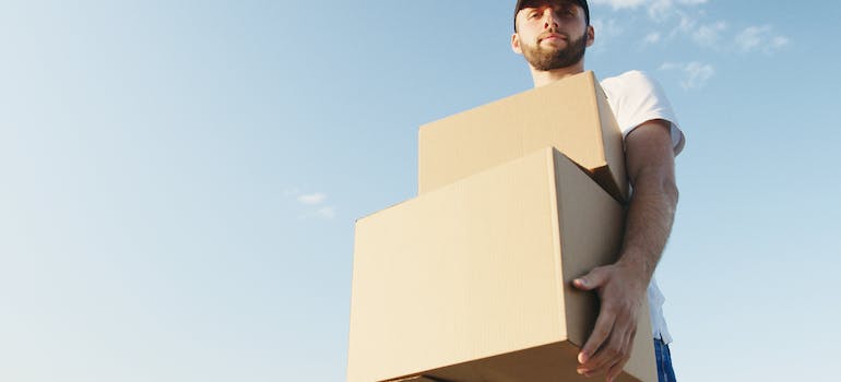 a man carrying some cardboard boxes in summer, which may be the perfect time to move