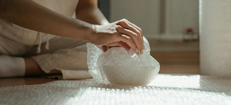 a person wrapping something into a bubble pack, which is one of the ways to keep valuables safe during your Burke move