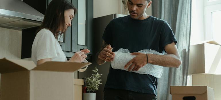 two people wrapping their belongings and putting them into boxes