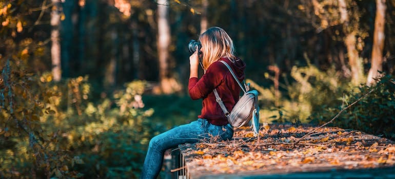 a woman taking pictures in a forest after successfully doing business with one of the moving companies Annandale VA offers