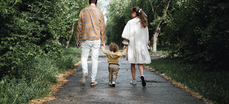 mother, father, and a child are walking down the road in a park