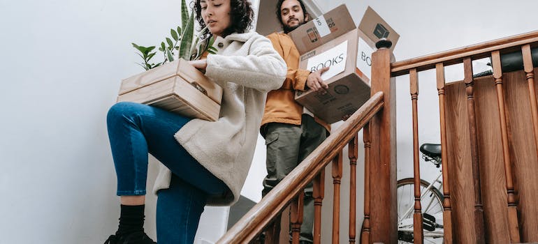 two people carrying boxes and a wooden crate with plants in it