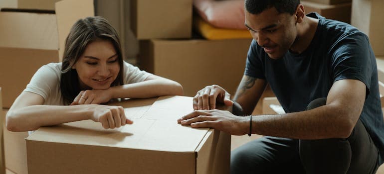 two people leaning on a cardboard box 