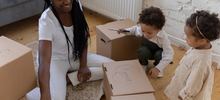 a mother and two children playing with cardboard boxes